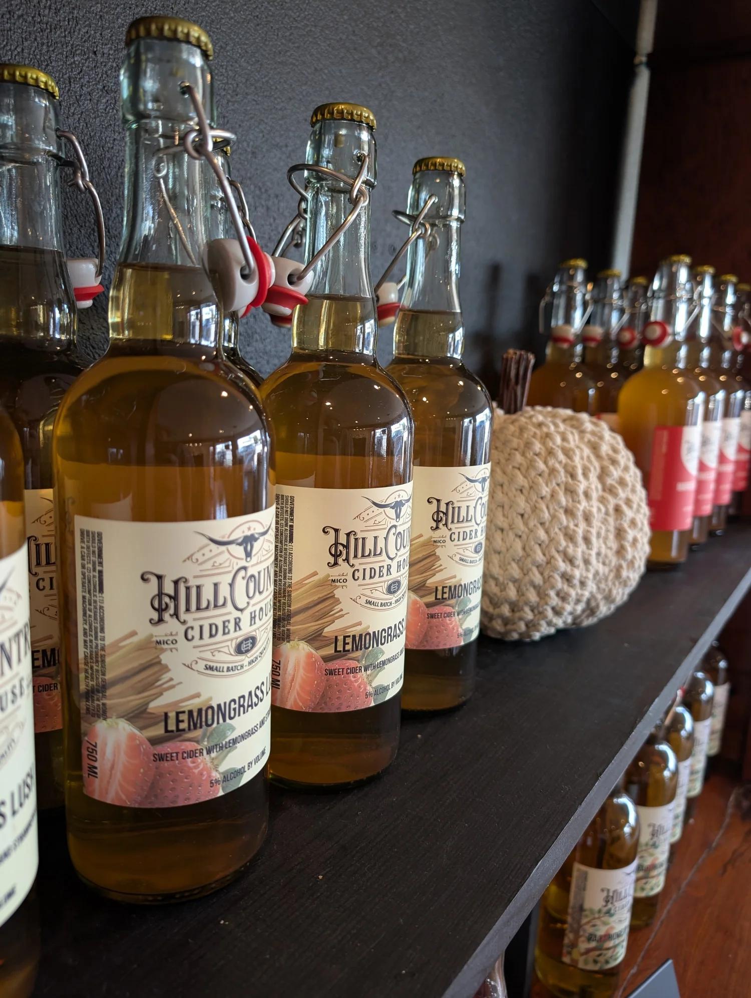 Cider bottles with swing-top caps on a dark wooden shelf